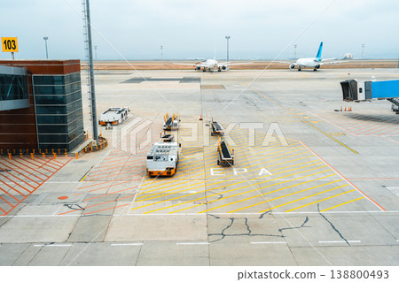 Airplane stands on runway near terminal in busy airport during cloudy day Airplane stands on runway near terminal in busy airport during cloudy day 138800493