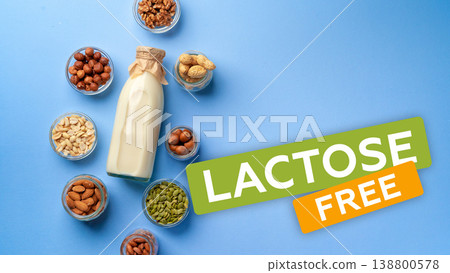 Different nuts and lactase milk on a blue surface with lactose free label 138800578