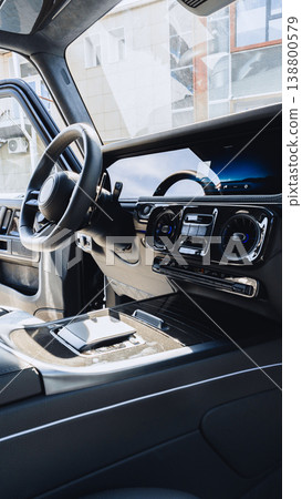 Interior view of a modern car dashboard with controls and steering wheel shown in detail 138800579