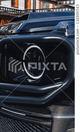 Close view of a vehicle's headlight and front grille during bright daylight 138800583