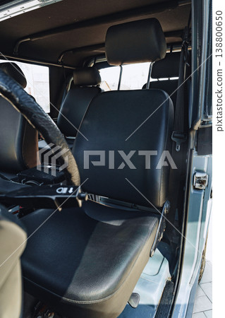 Interior view of a vehicle with black seats and steering wheel at a parking spot in daylight Interior view of a vehicle with black seats and steering wheel at a parking spot in daylight 138800650