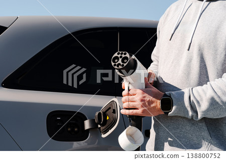 Person charges electric car at station during bright day Person charges electric car at station during bright day 138800752