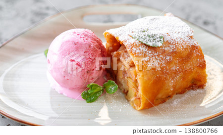 Delicious dessert with apple strudel and ice cream served on a white plate Delicious dessert with apple strudel and ice cream served on a white plate 138800766