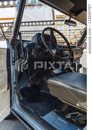 Old vehicle interior shows steering wheel, seat, and dashboard at an outdoor location Old vehicle interior shows steering wheel, seat, and dashboard at an outdoor location 138800767