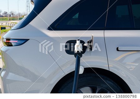 Electric car charger connects to car at charging station in daylight Electric car charger connects to car at charging station in daylight 138800798