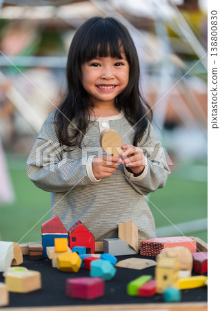 happy preschool child girl playing with wooden toy block at outdoor 138800830