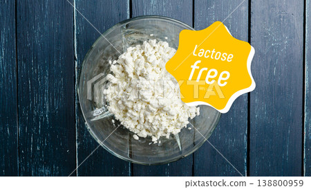 Fresh cottage cheese prepared without lactose and gluten in a clear bowl on wooden table 138800959