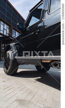 Black SUV parked on pavement outside a modern building during daylight hours Black SUV parked on pavement outside a modern building during daylight hours 138800980