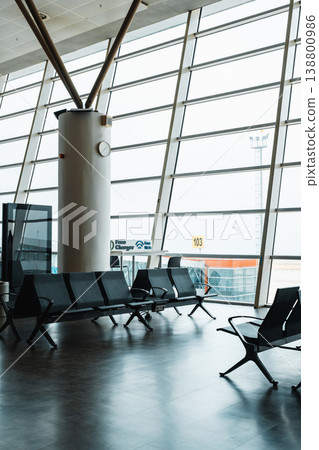 Busy airport terminal with empty seats and large windows during daylight Busy airport terminal with empty seats and large windows during daylight 138800986