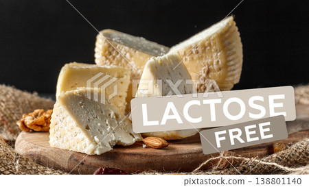 Cheese with no lactose on a wooden board with nuts and a dark background during the day 138801140