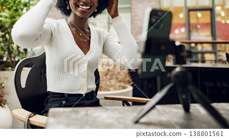 Young woman smiles while adjusting hair during video call at a cafe in the afternoon Young woman smiles while adjusting hair during video call at a cafe in the afternoon 138801561