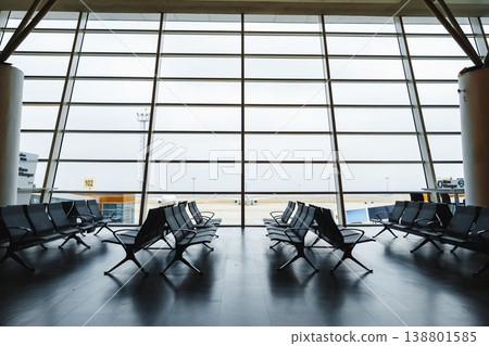 Waiting area at an airport with many empty chairs and a view outside Waiting area at an airport with many empty chairs and a view outside 138801585
