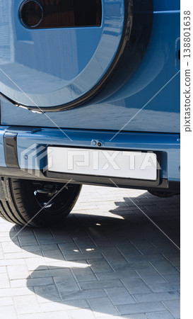 Car parked on a paved surface with a focus on the rear bumper and tire at midday Car parked on a paved surface with a focus on the rear bumper and tire at midday 138801638