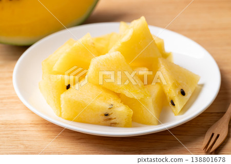 Sliced yellow watermelon on white plate with fork ready for eat Sliced yellow watermelon on white plate with fork ready for eat 138801678