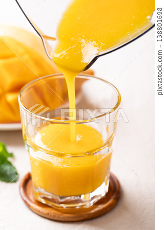Fresh mango smoothie in a glass with ripe mango slices, refreshing summer drink 138801698