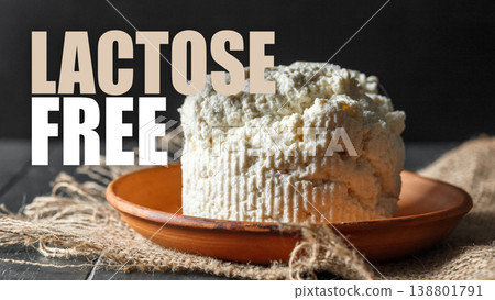 Lactose free cheese on a wooden plate placed on a dark background with beige cloth beneath 138801791