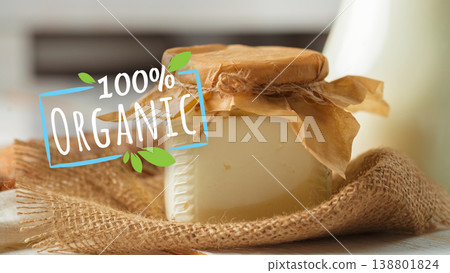 Creamy dairy product in a jar on a burlap surface with a milk bottle in the background Creamy dairy product in a jar on a burlap surface with a milk bottle in the background 138801824