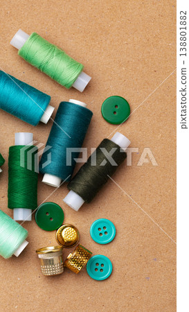 Spools of thread and buttons spread on a craft workspace at midday 138801882