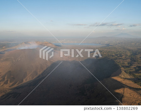 View of volcanic landscape with smoke from crater during day View of volcanic landscape with smoke from crater during day 138802269