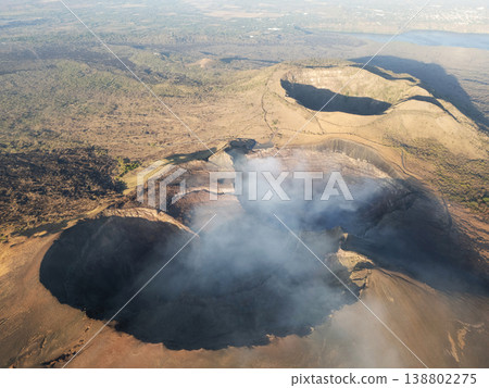 Volcano crater with smoke in aerial view over landscape Volcano crater with smoke in aerial view over landscape 138802275
