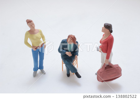 Miniature Figures Conversing Around Seated Person Miniature Figures Conversing Around Seated Person 138802522