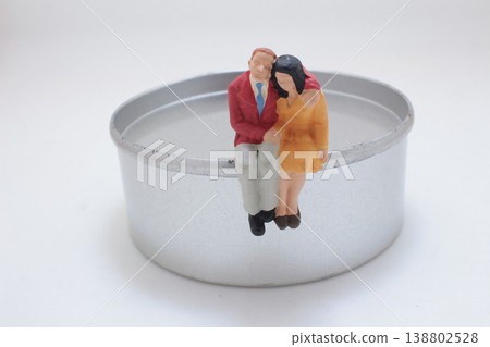Miniature Couple Sitting On Metal Lid 138802528