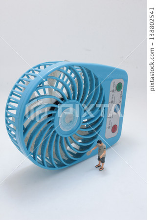 Miniature Figure Beside Blue Desk Fan 138802541