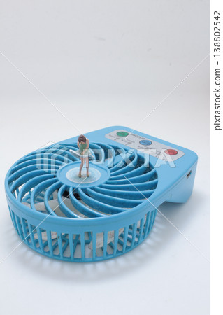 Miniature Figure Atop Blue Desk Fan Miniature Figure Atop Blue Desk Fan 138802542
