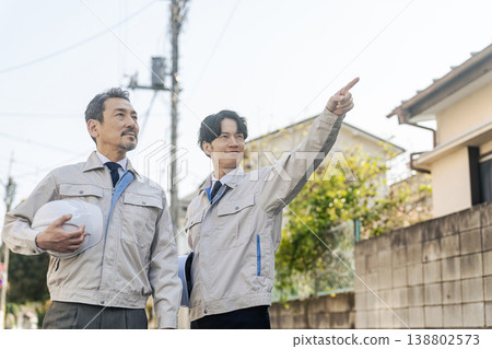 A group of male workers standing in a residential area A group of male workers standing in a residential area 138802573