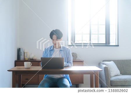 一個男人在房間裡使用筆記本電腦 138802602