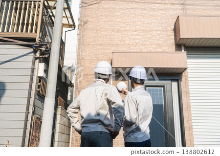 A group of male workers inspecting a house. A group of male workers inspecting a house. 138802612