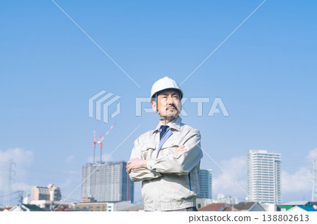 A male worker gazes into the distance in front of a city. A male worker gazes into the distance in front of a city. 138802613