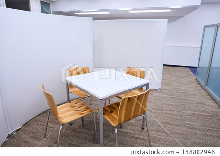 The office has a meeting space with a simple white table and wooden chairs. 138802946