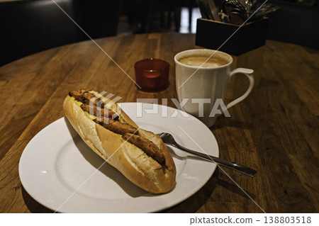 A cafe scene featuring a baguette sandwich filled with curry-flavored grilled chicken and coffee. A cafe scene featuring a baguette sandwich filled with curry-flavored grilled chicken and coffee. 138803518