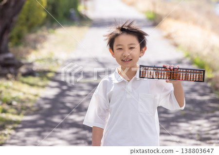 A young boy in elementary school, smiling, holding an abacus. A young boy in elementary school, smiling, holding an abacus. 138803647
