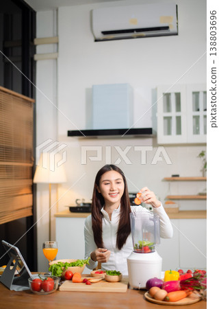 Healthy Asian woman making detox smoothie at home kitchen, adding fresh fruits and vegetables to blender. Clean eating, nutrition diet, wellness lifestyle 138803696
