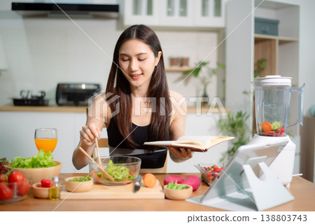 Asian woman planning healthy meals with fresh vegetables and smoothie in modern kitchen. Clean eating, nutrition, fitness lifestyle and wellness at home concept. Asian woman planning healthy meals with fresh vegetables and smoothie in modern kitchen. Clean eating, nutrition, fitness lifestyle and wellness at home concept. 138803743