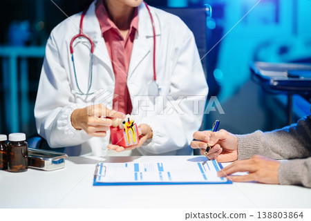 Asian female dentist explains dental model and treatment form to patient during consultation Asian female dentist explains dental model and treatment form to patient during consultation 138803864