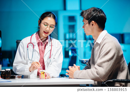 The dentist explains dental care using a model with a smiling patient. 138803915