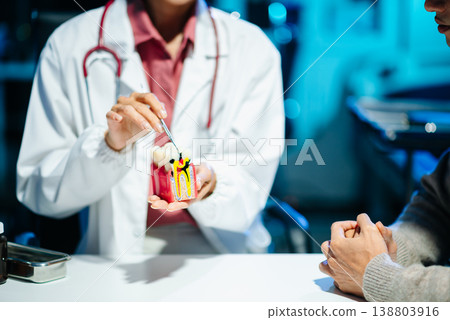 The dentist explains dental care using a model with a smiling patient. The dentist explains dental care using a model with a smiling patient. 138803916