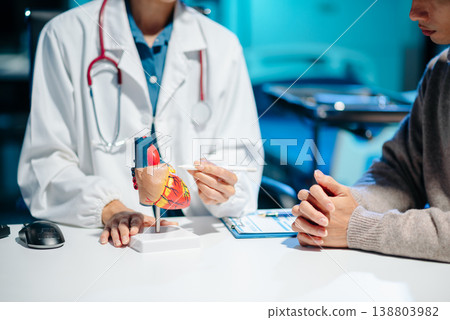 Doctor explaining human heart model to patient during consultation in a medical office 138803982