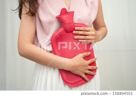 Woman using hot water bottle to relieve menstrual abdominal pain. Woman using hot water bottle to relieve menstrual abdominal pain. 138804501
