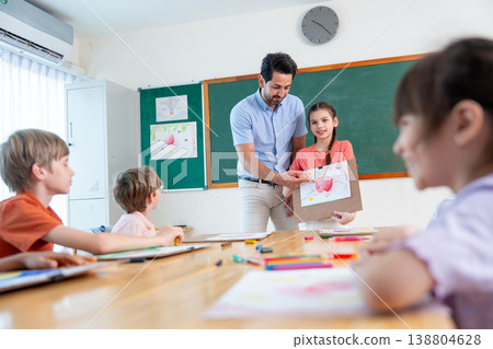 The teacher try to encorage lovely girl to present his painting also explain the meaning of it in front of the classroom and friends also interest in his creation. 138804628