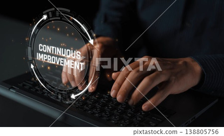 Close-up of hands typing on a keyboard with a futuristic digital interface highlighting the concept of continuous improvement in a dark, professional setting. Sigmoid 138805756