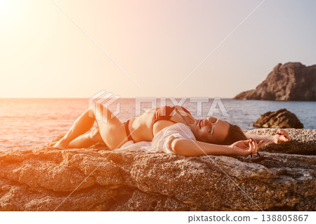 Woman beach sunset Relaxed woman lying on coastal rocks during golden hour at the seaside with copy space Woman beach sunset Relaxed woman lying on coastal rocks during golden hour at the seaside with copy space 138805867