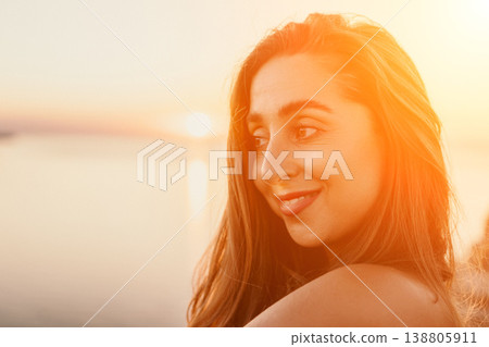Sunset woman portrait captured during golden hour at the beach while she looks away with a gentle smile Sunset woman portrait captured during golden hour at the beach while she looks away with a gentle smile 138805911