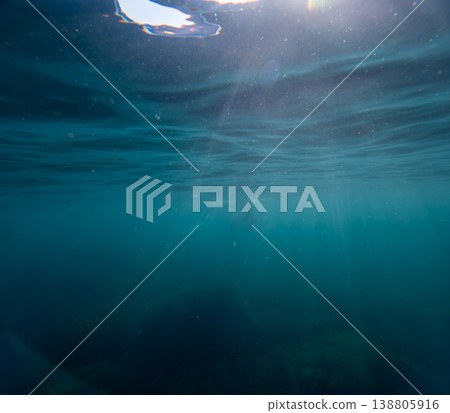 Underwater Sunlight Ocean rays penetrate the blue water surface creating a serene and atmospheric deep sea background for nature concepts 138805916