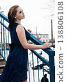 Young woman in blue dress standing on snowy bridge in winter, cold weather fashion concept 138806108