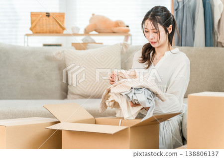 一位年輕女子正在打包搬家,整理不需要的物品,租房,訂閱,網上購物,使用跳蚤市場應用程序 一位年輕女子正在打包搬家,整理不需要的物品,租房,訂閱,網上購物,使用跳蚤市場應用程序 138806137
