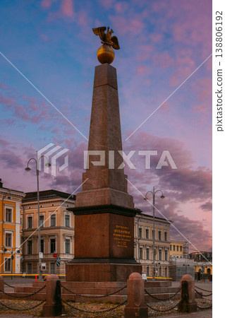The Stone of the Empress (Keisarinnankivi) obelisk monument standing prominently in Market Square with historic buildings and the Uspenski Cathedral under a stunning sunset sky 138806192